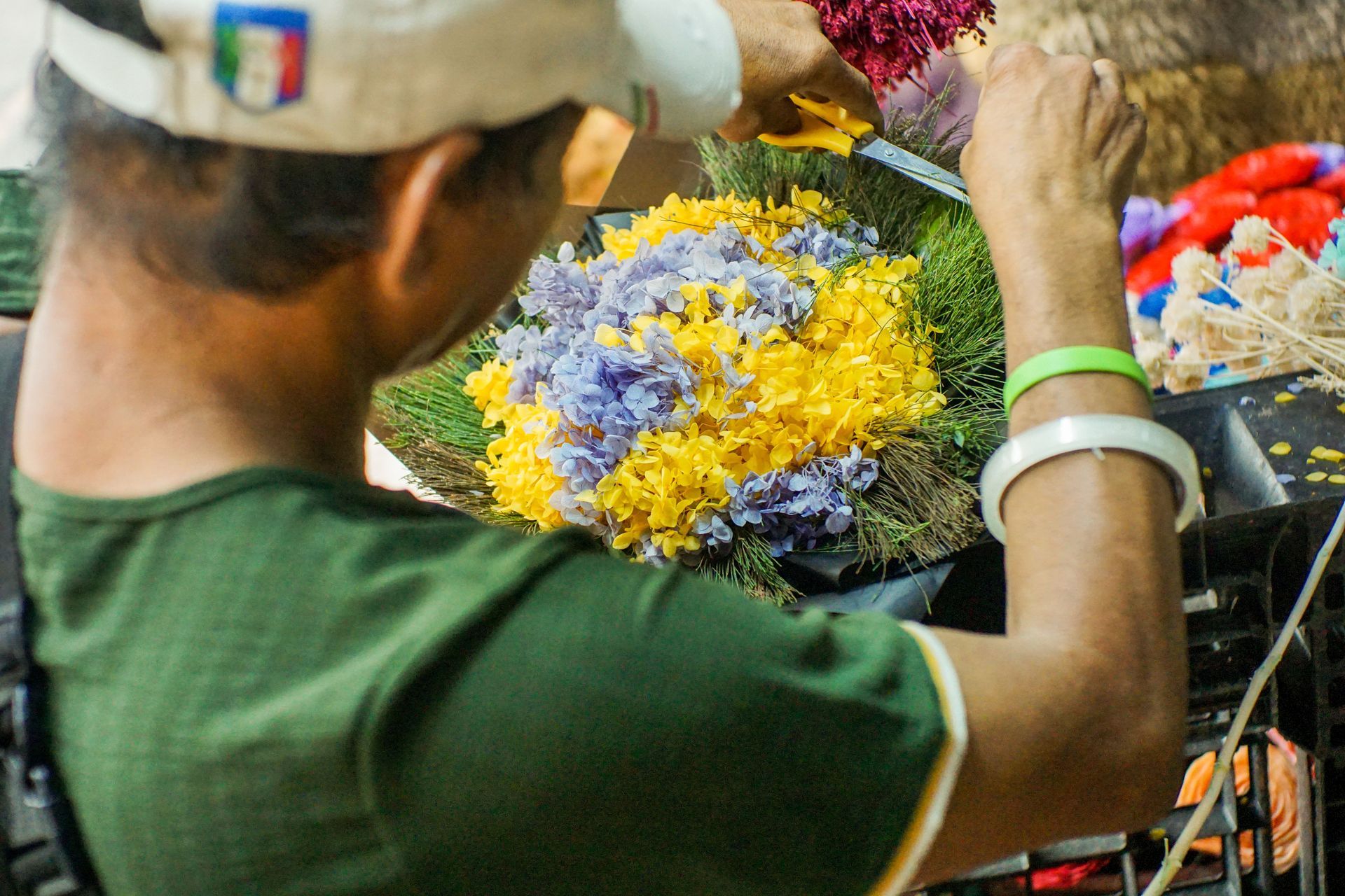 Person arranging colorful flowers at a market stall