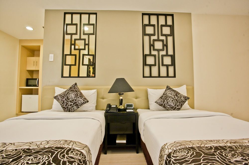 Tidy hotel room with two twin beds, patterned pillows, and wall decor.