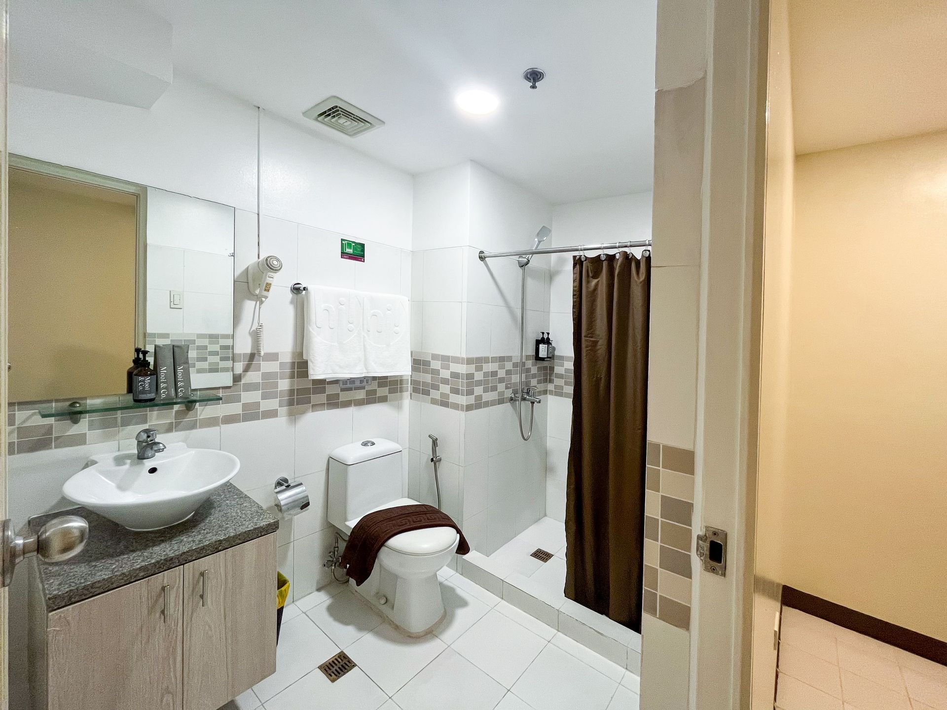 A bathroom with a sink , toilet , shower and mirror.