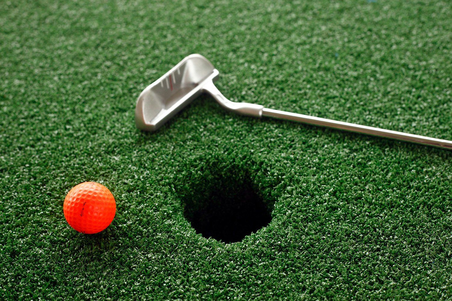A golf ball is sitting next to a golf club on a golf course.