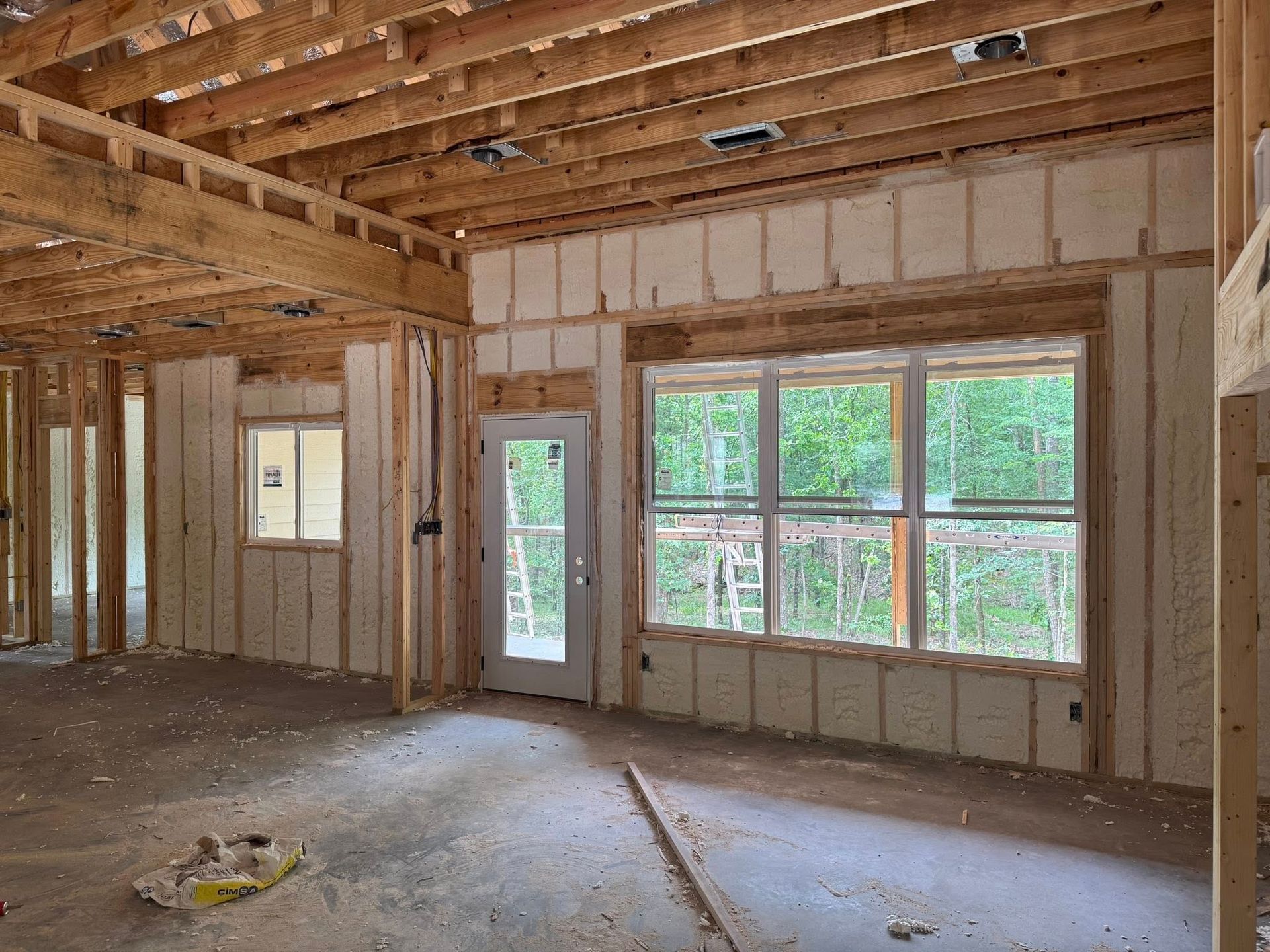 A room with a lot of windows and a door in a house under construction.