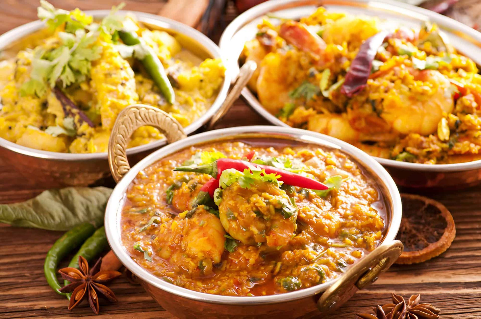 Three Bowls Of Indian Food Are Sitting On A Wooden Table — Punjabi Sunrise Restaurant In Alexandra Hills, QLD