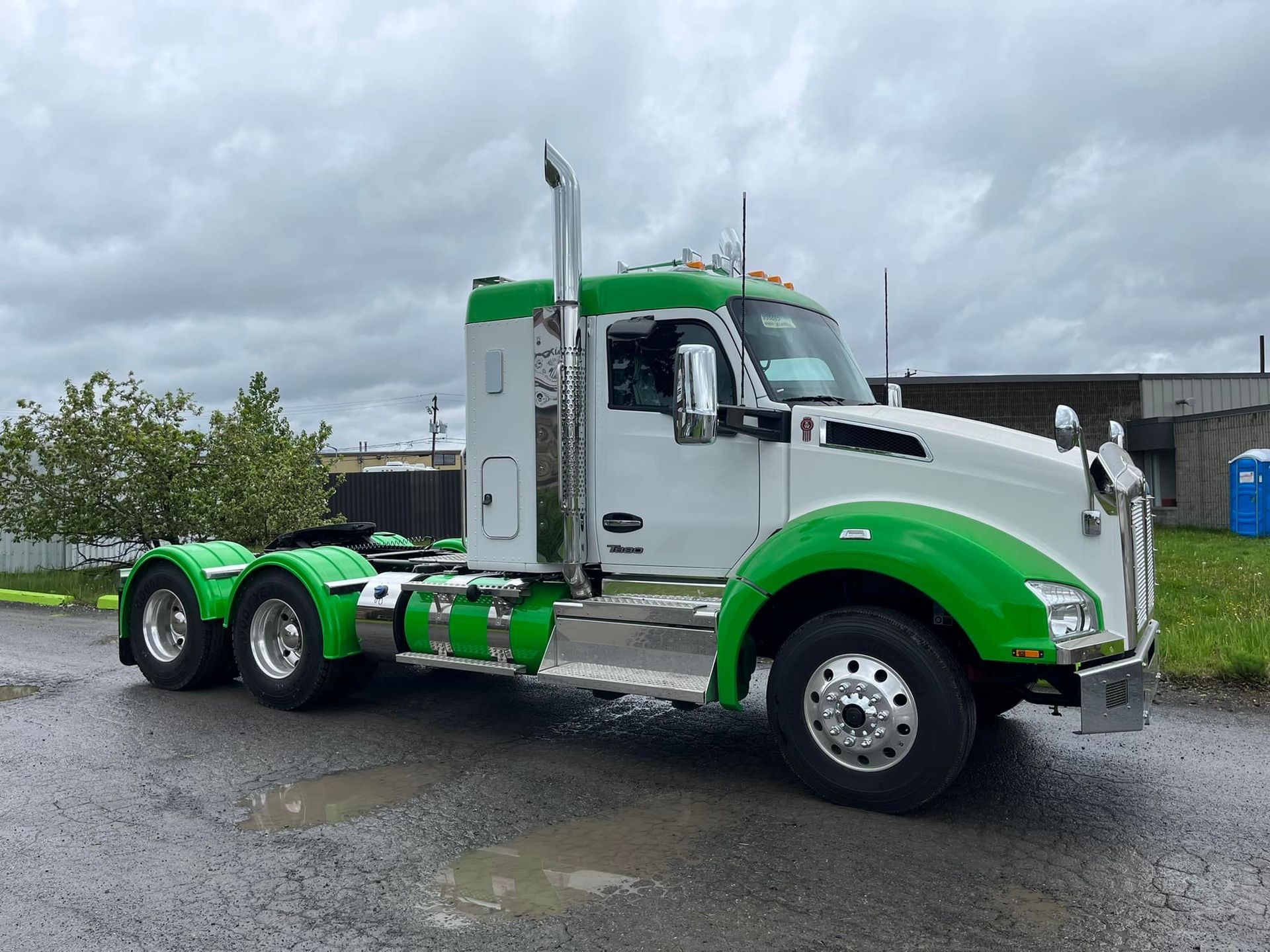 Semi-camion blanc et vert sur une surface pavée sous un ciel nuageux.