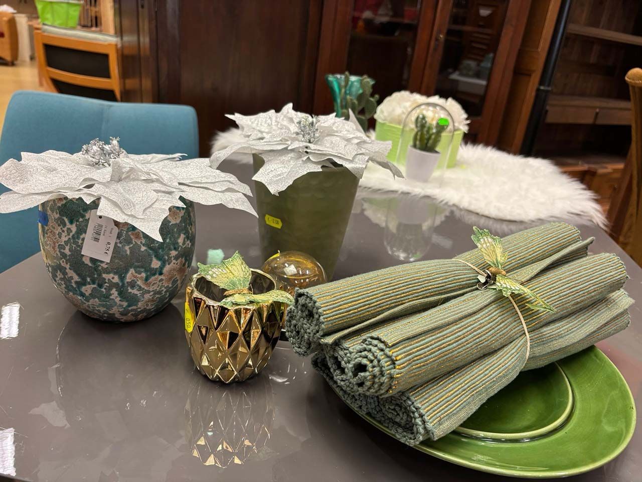Decoratieve bundels en geschenkmanden op een tafel, waaronder groene rollen en zilverkleurig verpakte dozen.