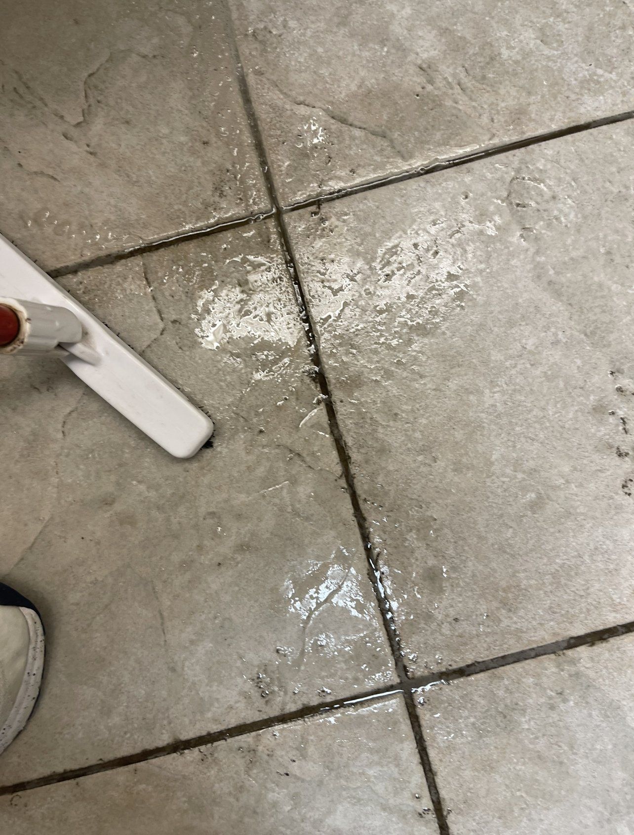 A person is cleaning a tile floor with a mop.