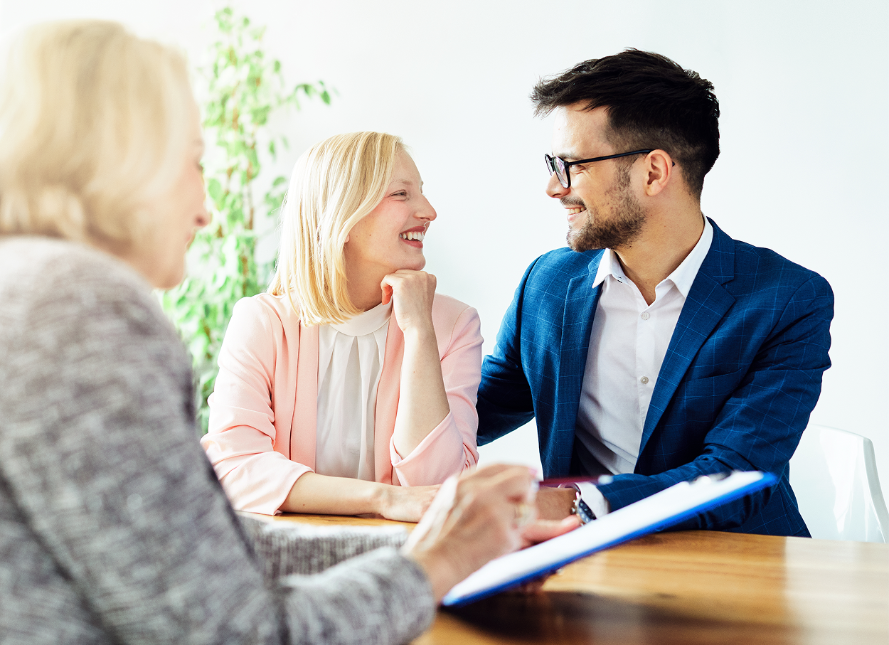 A man and a woman are sitting at a table talking to a woman.