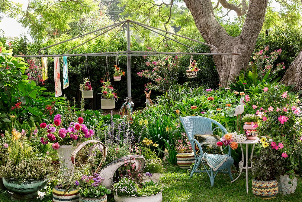 chairs in a garden with flowers in pots and washing line behind