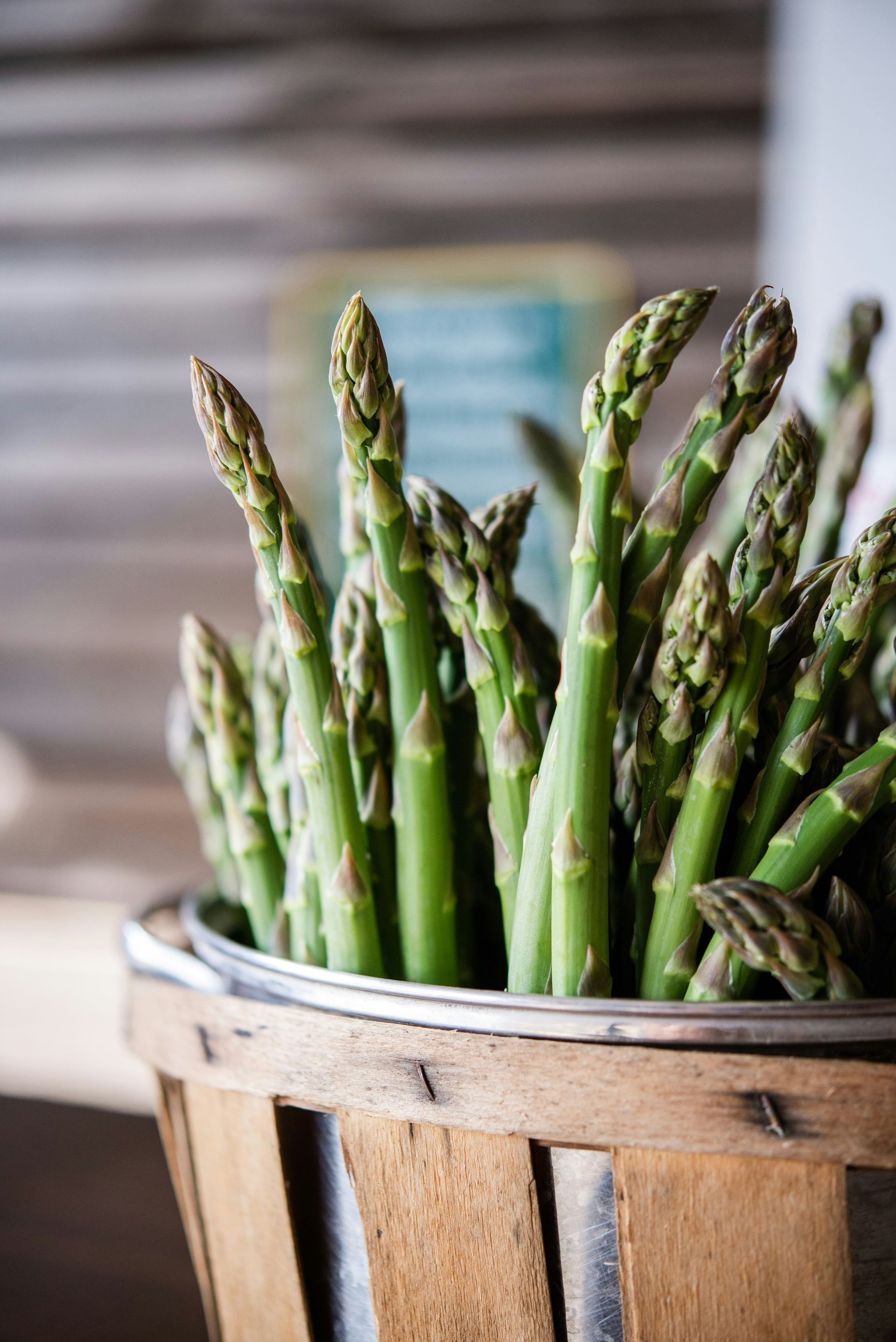 Asparagus spears in a wooden basket. Bright green stalks with dark green tips.