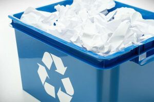 A blue recycling bin filled with white paper.