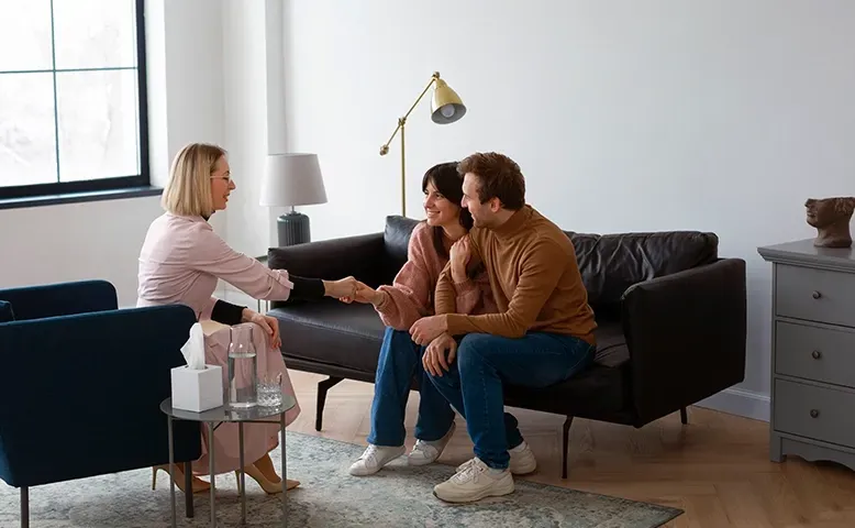 Therapist speaking with a couple on a sofa in a bright living room