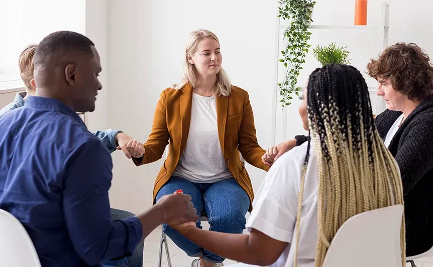 Small group in a bright office discussing around a seated woman leading a meeting