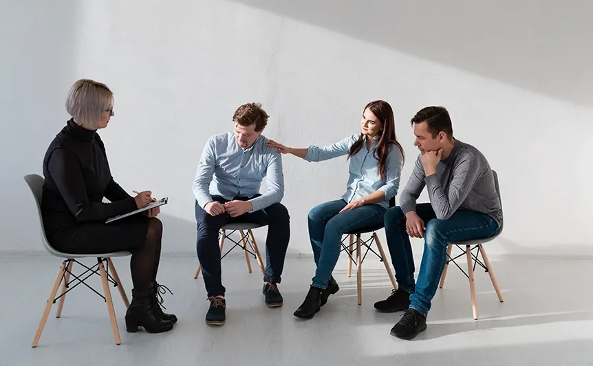 Four people sitting on chairs in a discussion, one woman gesturing while talking in a bright studio.