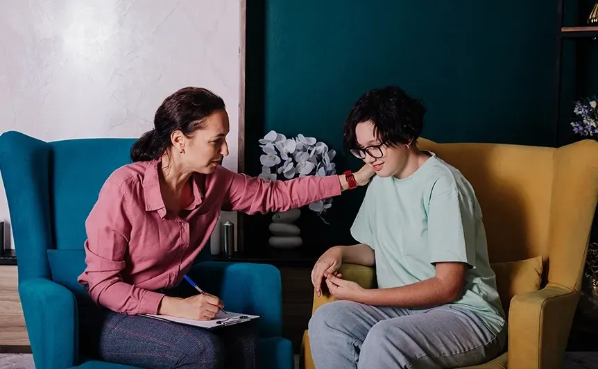Woman comforts a seated person on a couch in a colorful living room