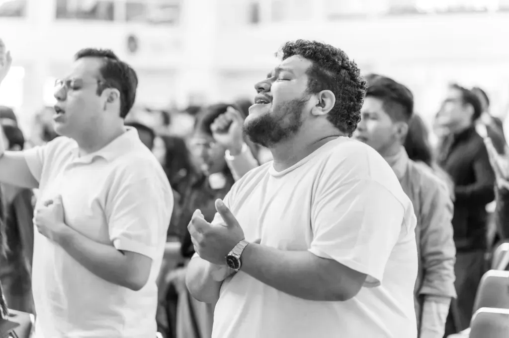 Crowd of people standing and clapping during a gathering, with one man smiling in the foreground
