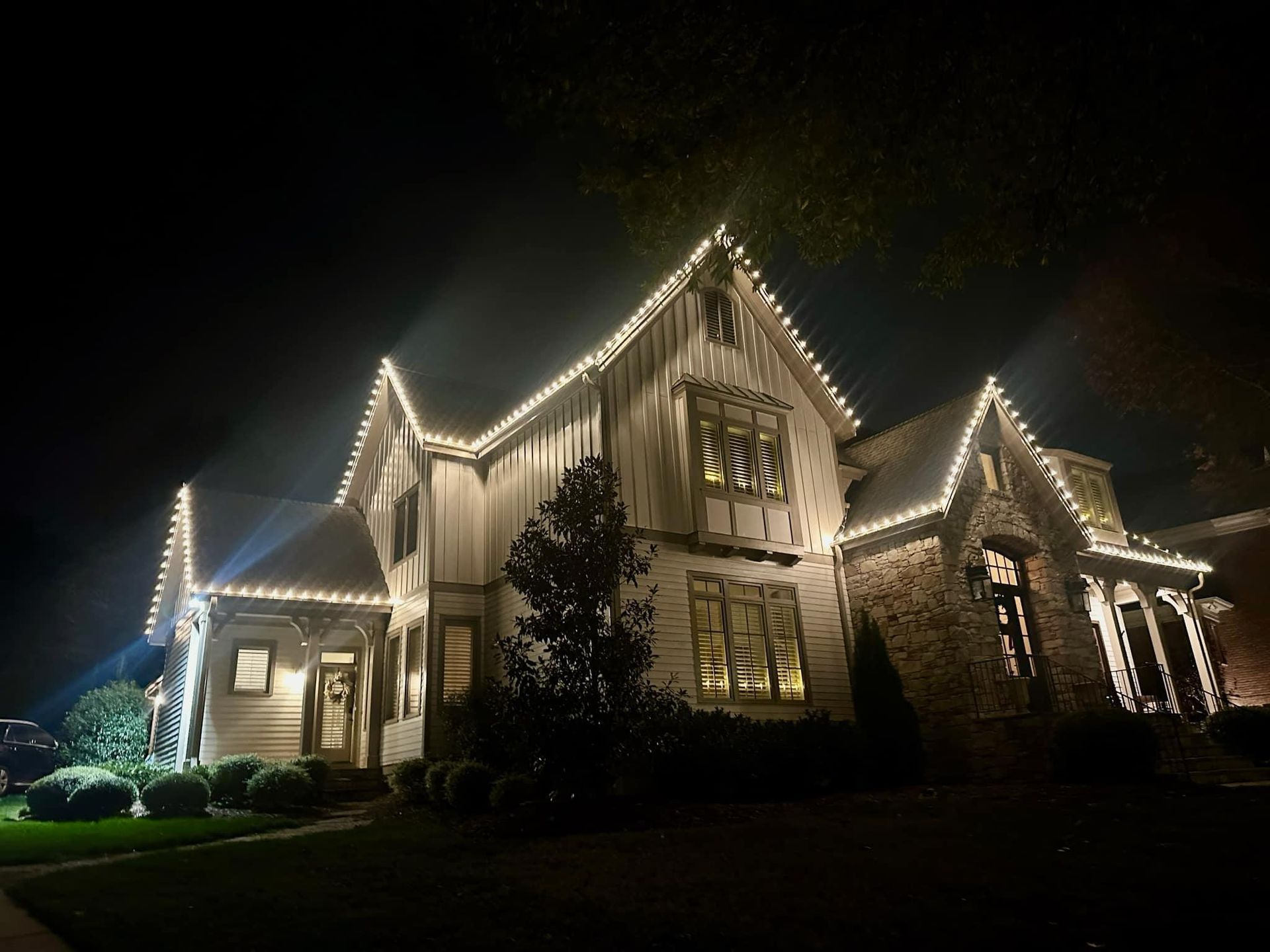 A large house is lit up with christmas lights at night.