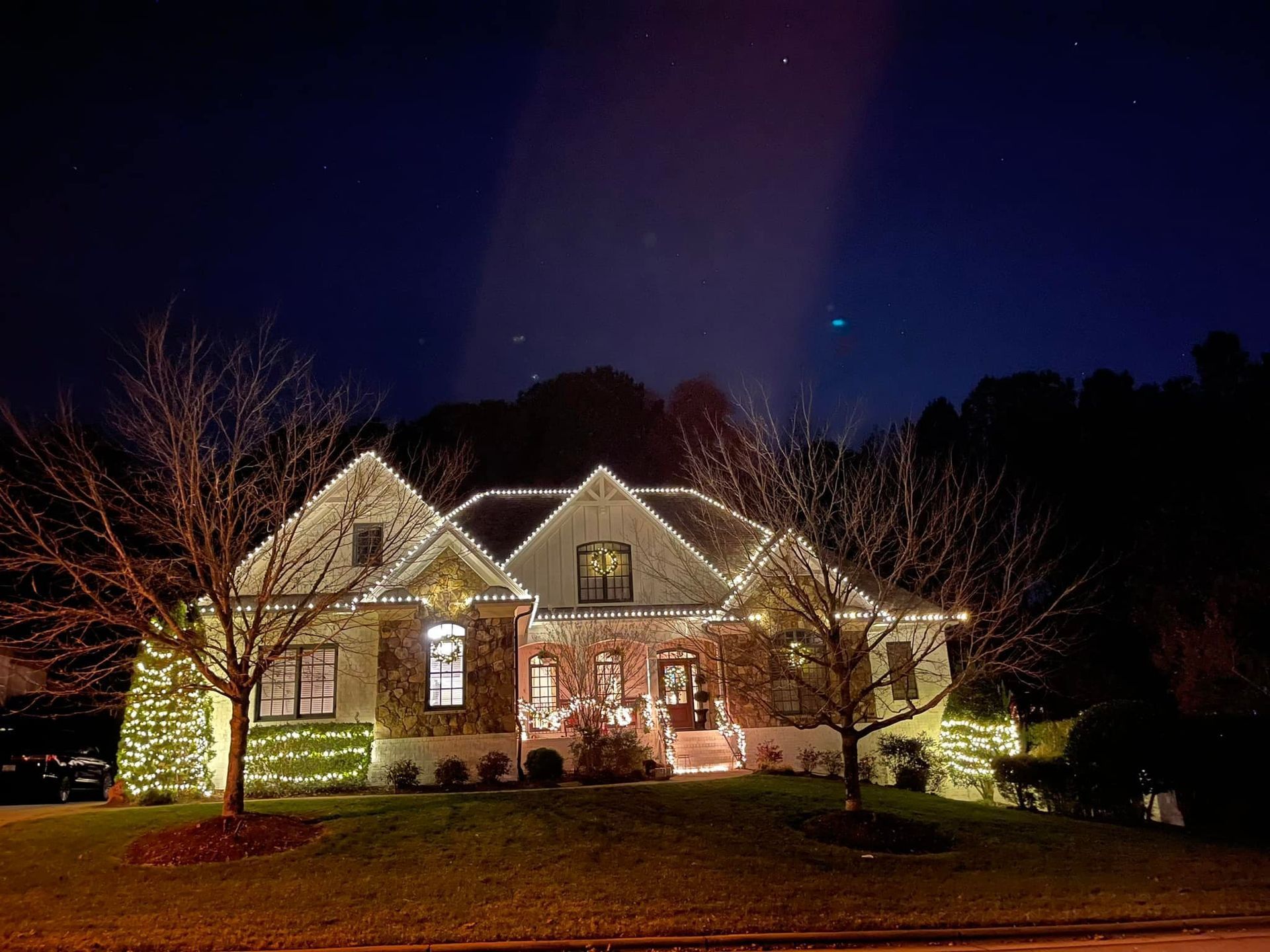 A large house is lit up with christmas lights at night.