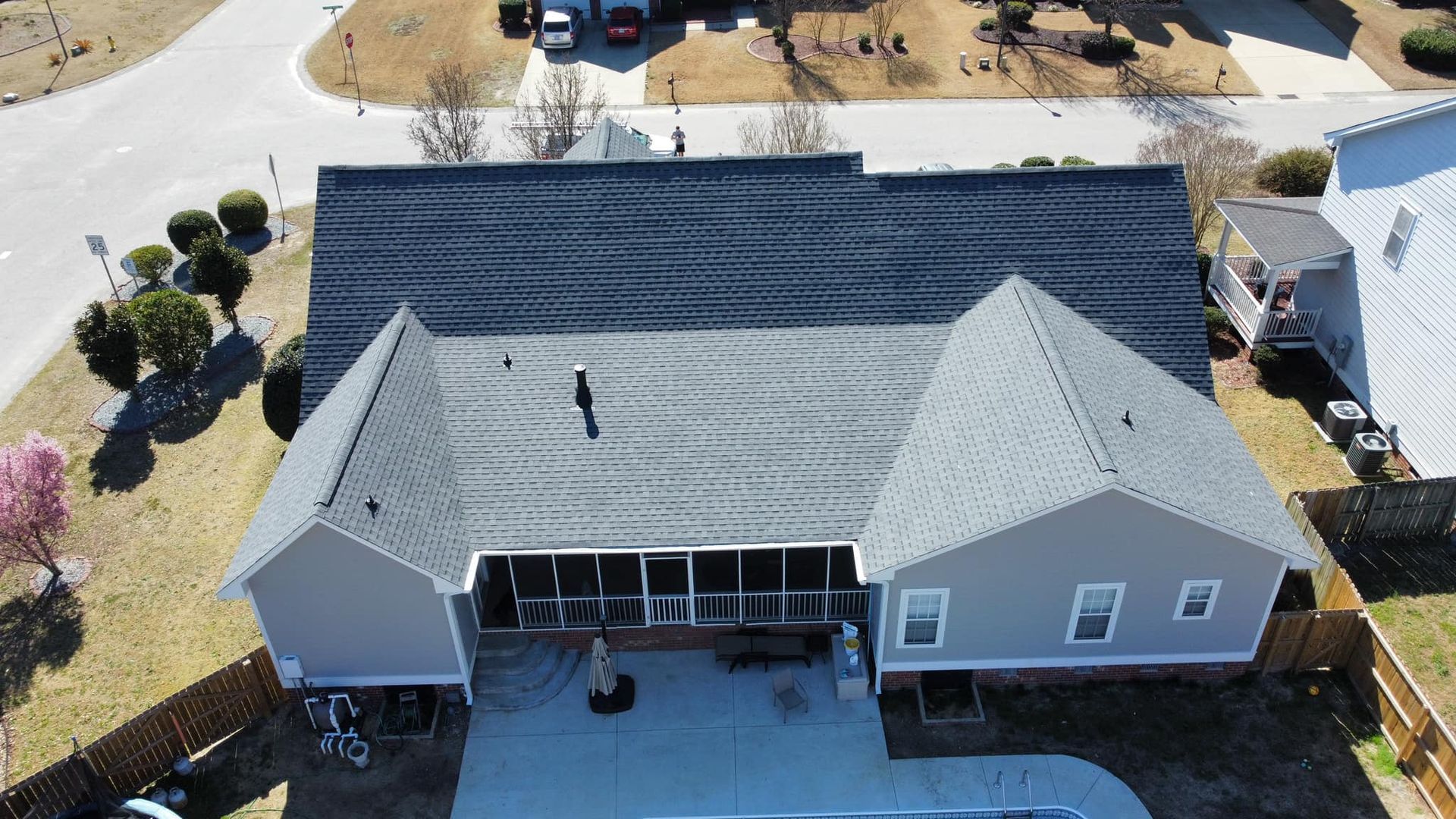An aerial view of a house with a gray roof and a pool.