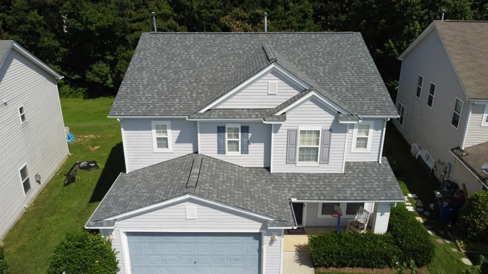 An aerial view of a white house with a gray roof.