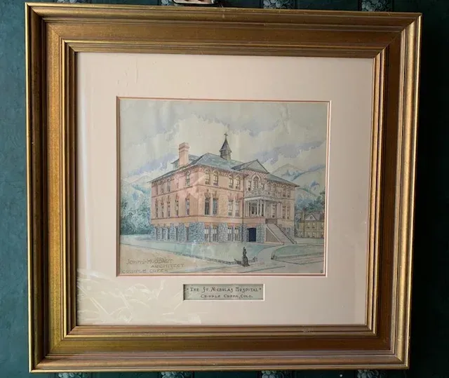 A framed painting of a large building with a name tag on it