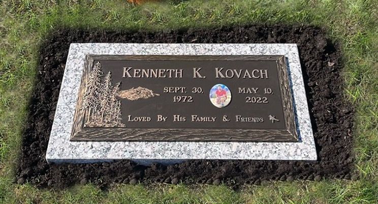 Misty bronze grave marker with a wilderness scene