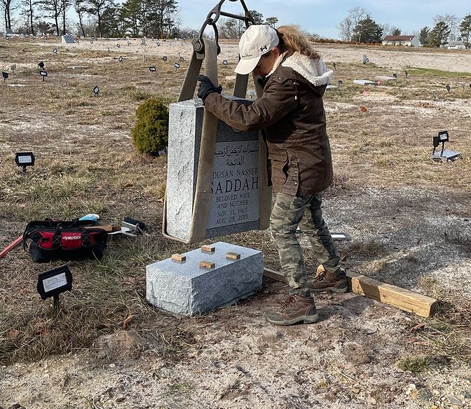 employee lowering headstone onto its base at the cemetery