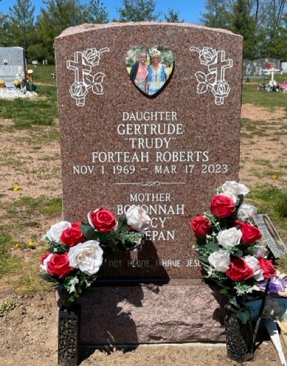 A red granite headstone with a glazed porcelain mother-daughter image shaped like a heart.