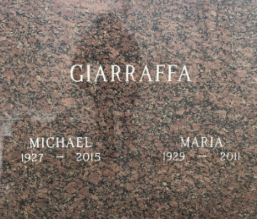 A red granite companion mausoleum door with the engraved surname of the couple. 