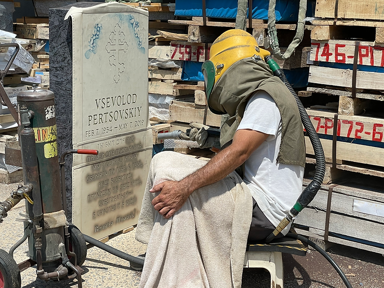 Worker inscribing name and dates on a tombstone