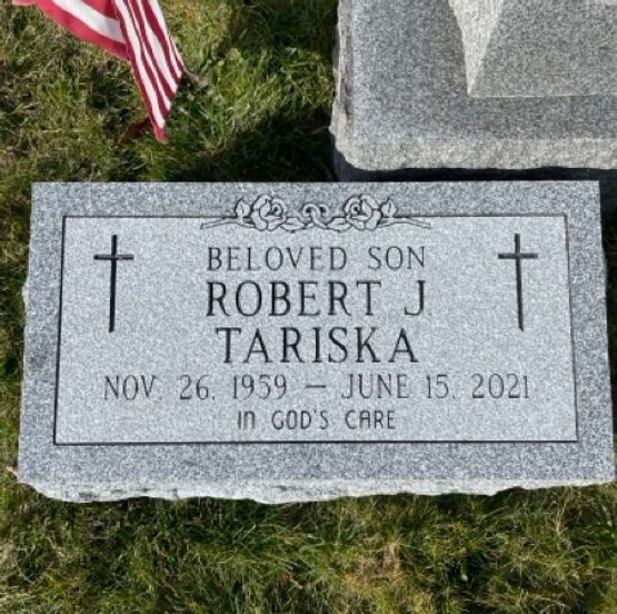A flat granite footstone with two Celtic crosses and a floral motif.