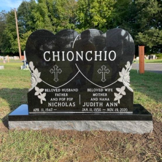 Double heart-shaped memorial made of polished black granite. Two crosses and floral carvings complete the design.