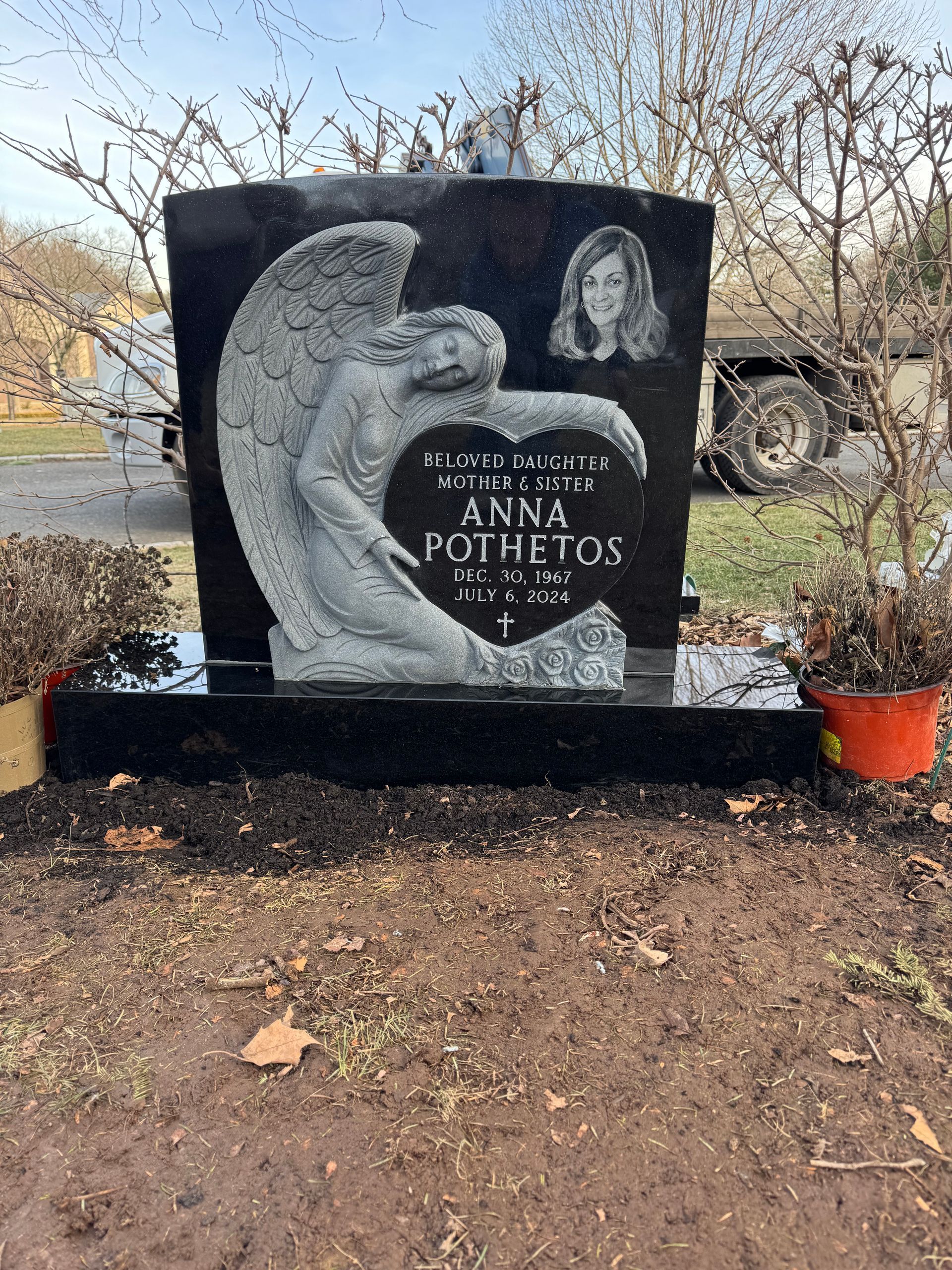 Black granite headstone with an angel carving, photo of a woman, and name