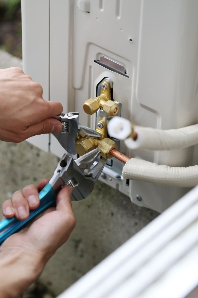 A Person Is Working On An Air Conditioner With A Wrench And Pliers — Newcastle Air & Refrigeration In Lake Macquarie, NSW