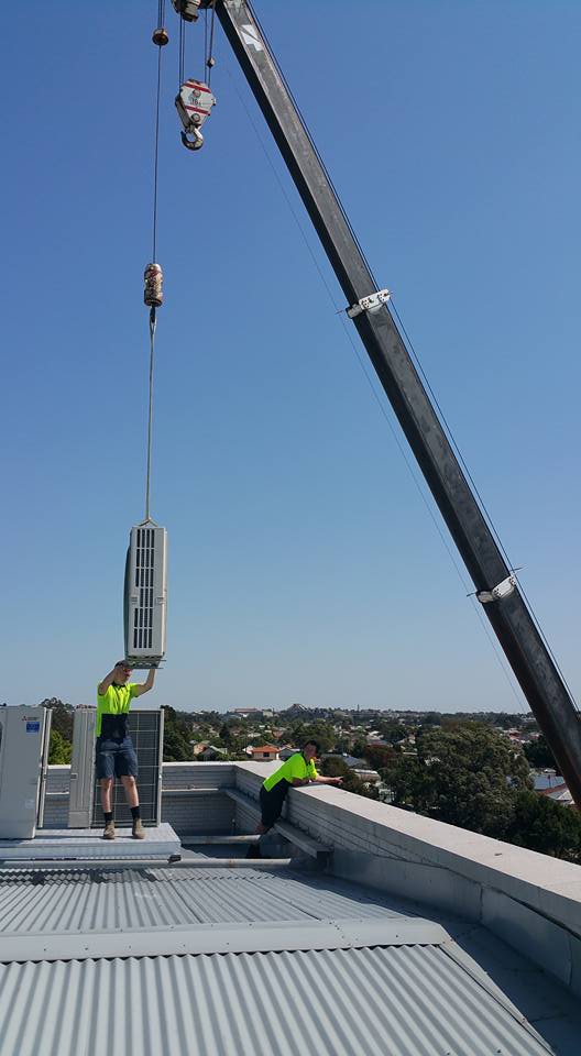 Crane Lifting Inverter Air Conditioner on a  Roof— Newcastle Air & Refrigeration In New Lambton, NSW