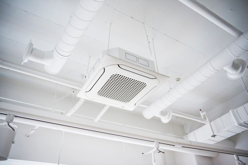 A White Air Conditioner Is Hanging From The Ceiling Of A Building — Newcastle Air & Refrigeration In Newcastle, NSW
