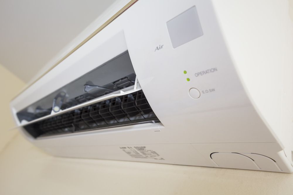 A White Air Conditioner Is Hanging On A Wall — Newcastle Air & Refrigeration In Newcastle, NSW