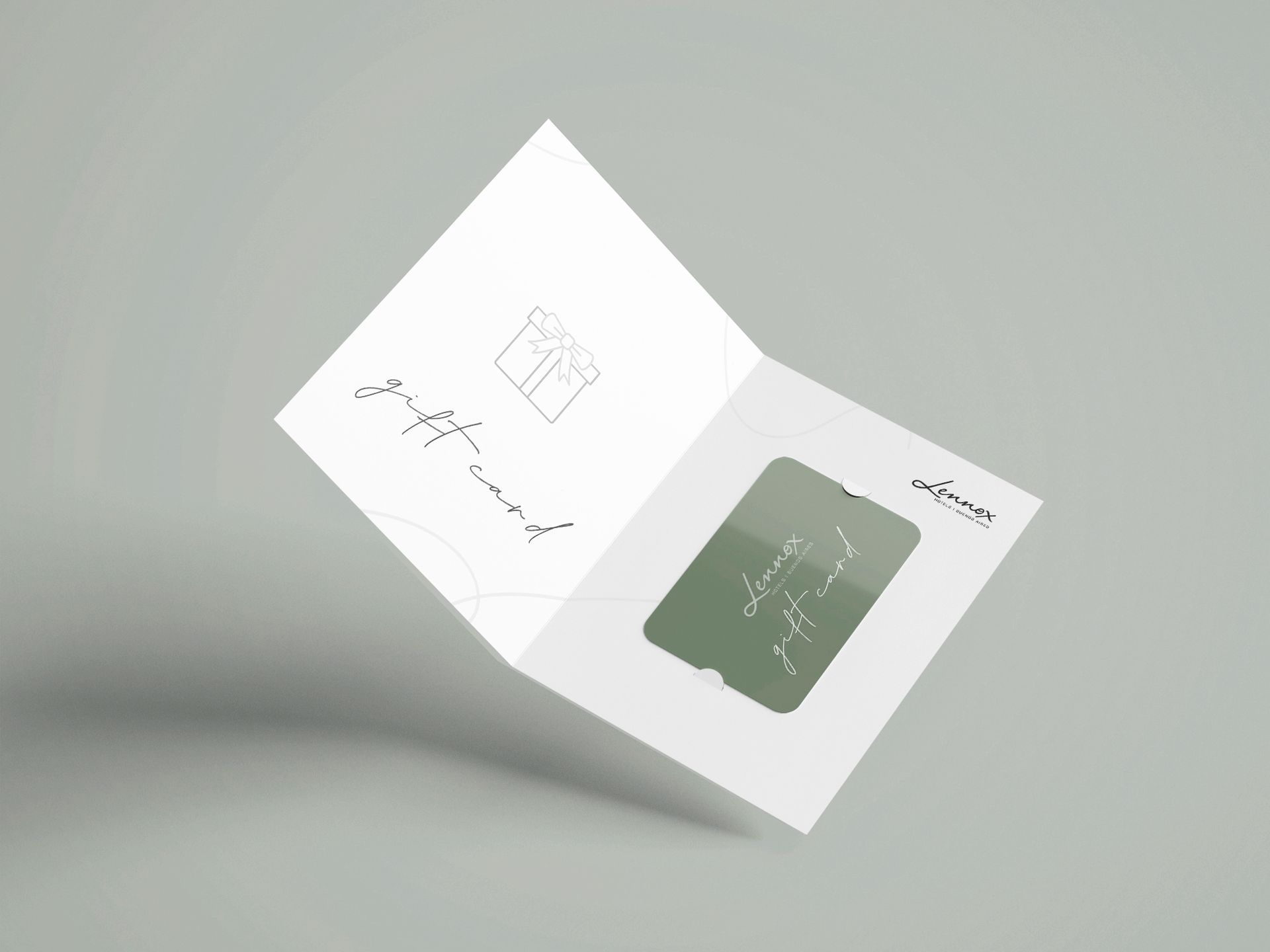 Folleto blanco abierto con bocetos minimalistas y un panel cuadrado verde sobre un fondo gris.