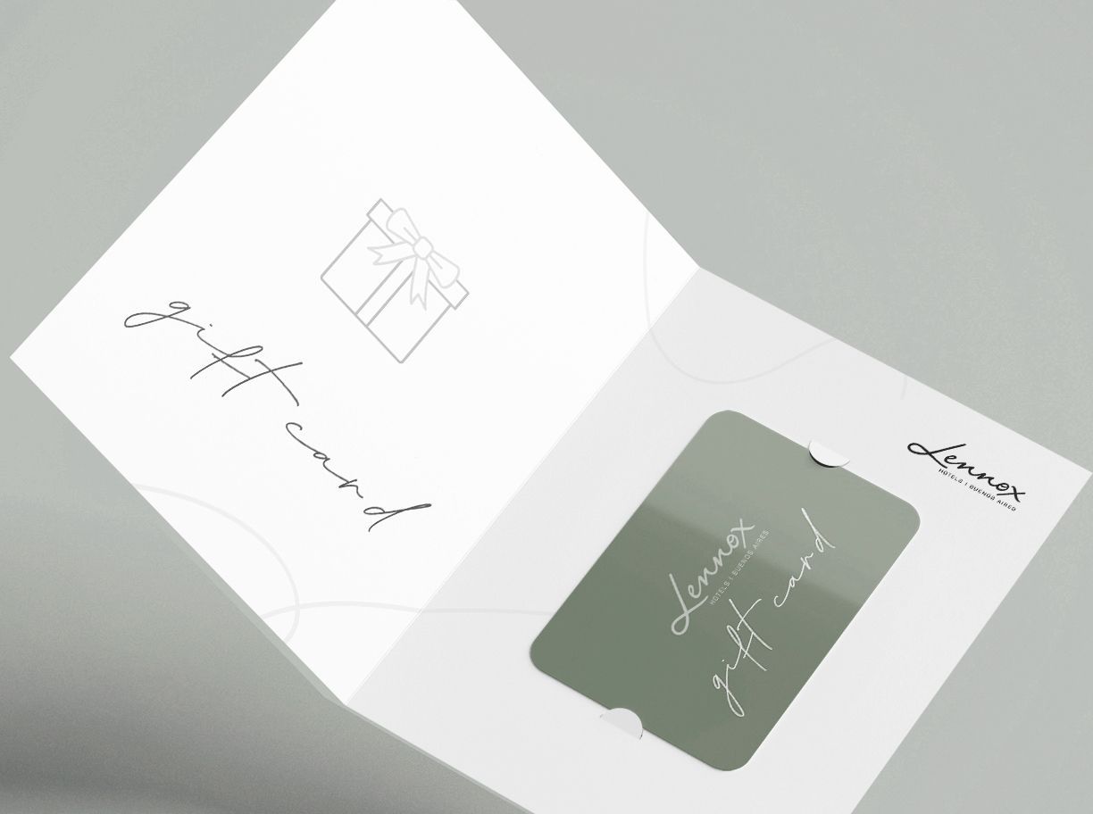 Tarjeta blanca abierta con texto cursivo negro y un pequeño inserto verde sobre una superficie gris.
