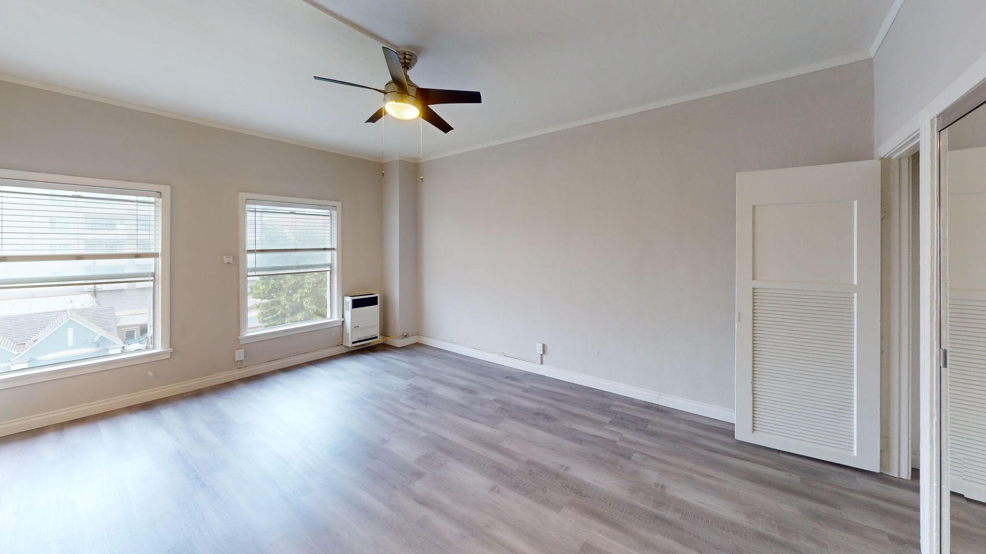 Empty room with two windows, a closet, and ceiling fan. Gray floors and off-white walls.