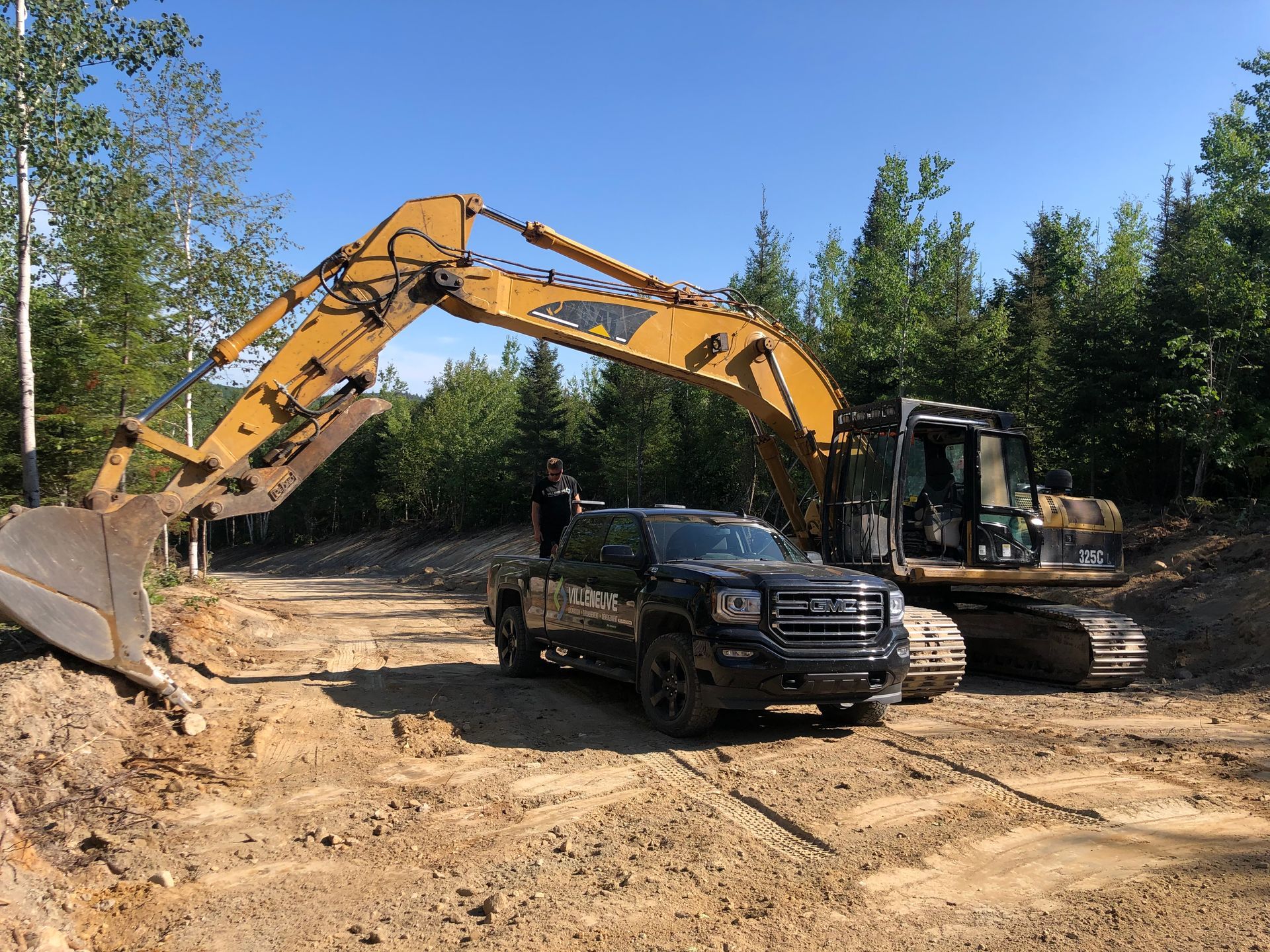 Un camion est garé à côté d'une grande excavatrice dans un champ de terre.