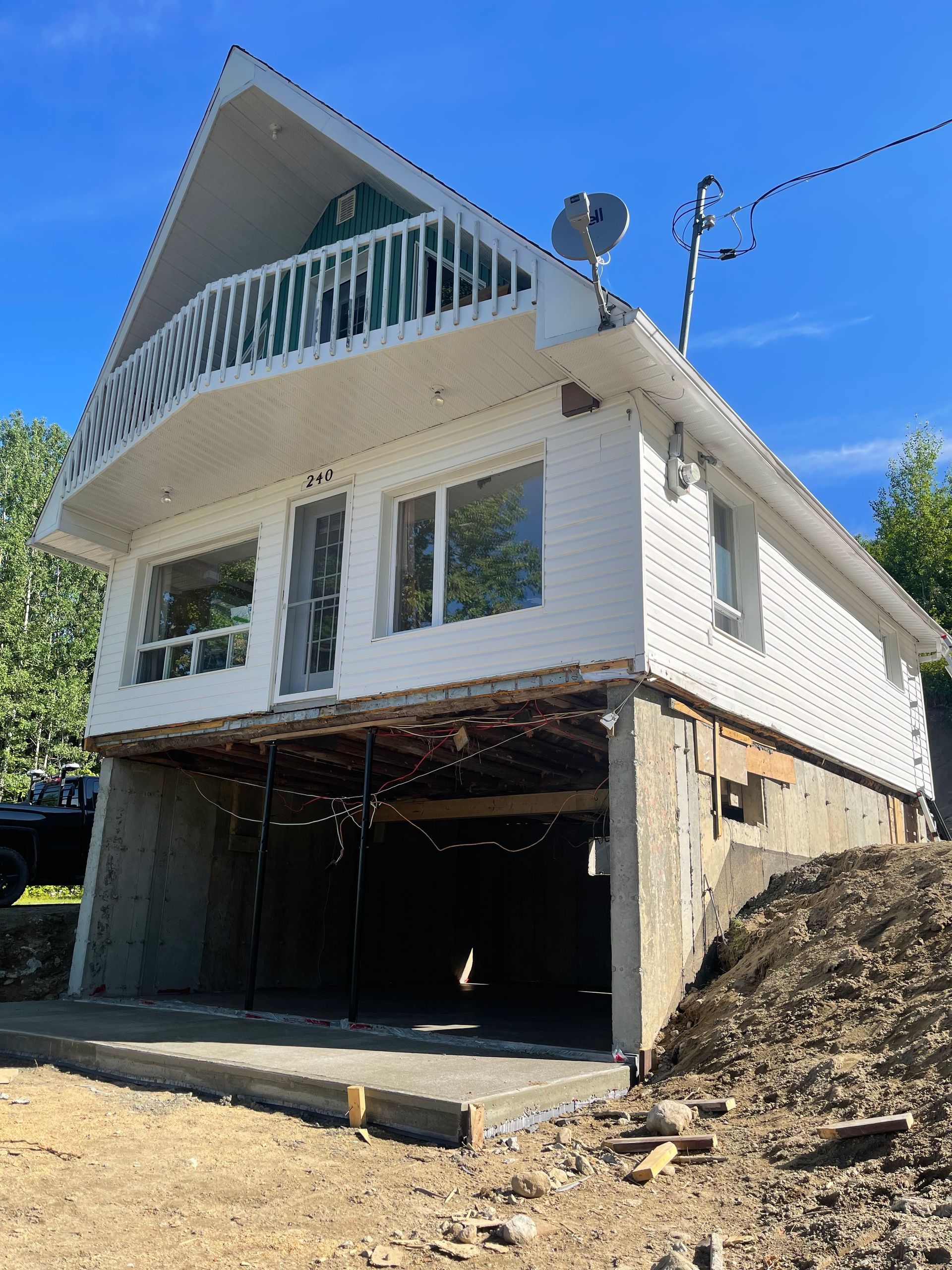 Une maison blanche avec un balcon est située au sommet d'une colline de terre.