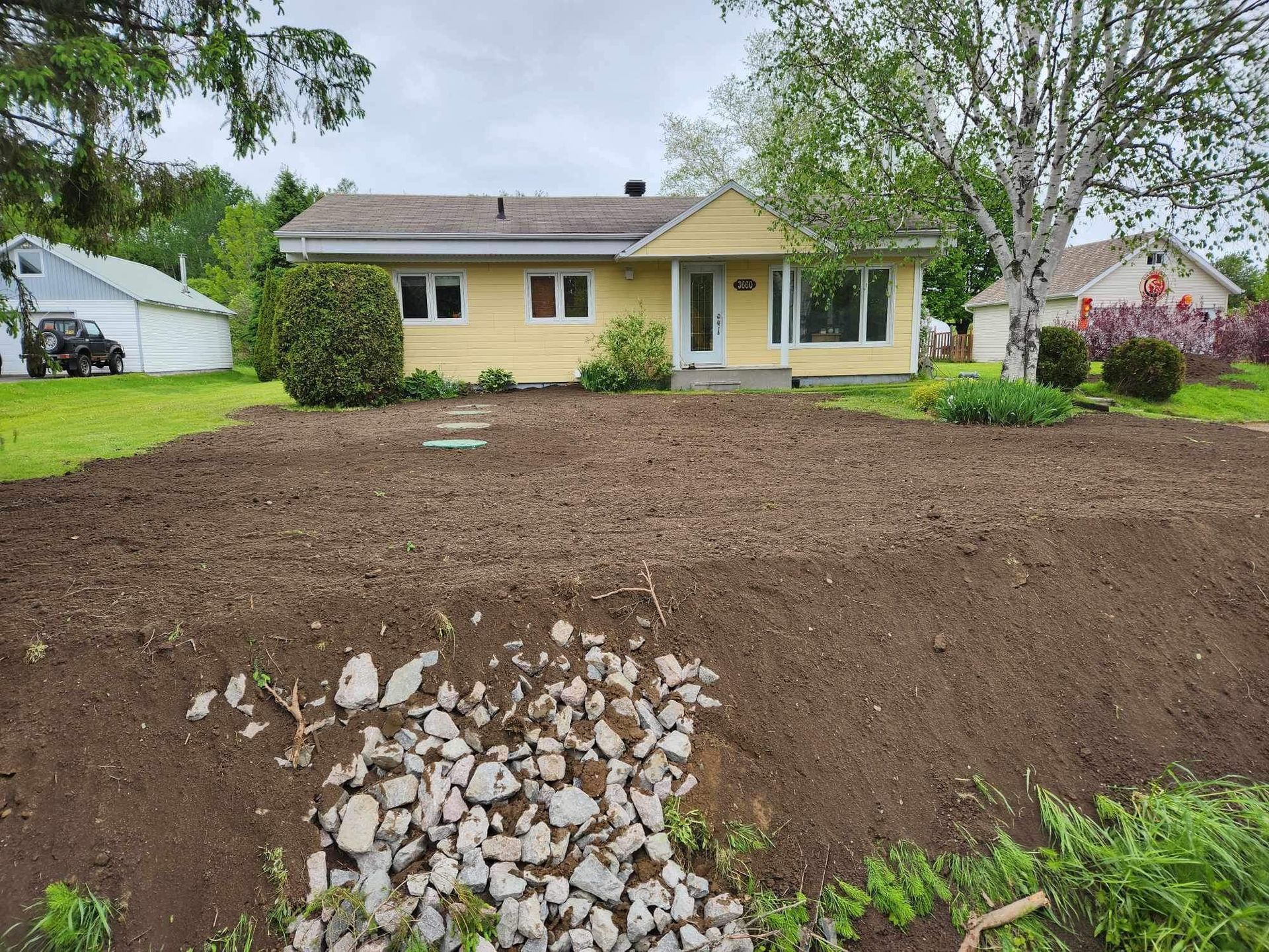 Une maison jaune avec beaucoup de terre devant.