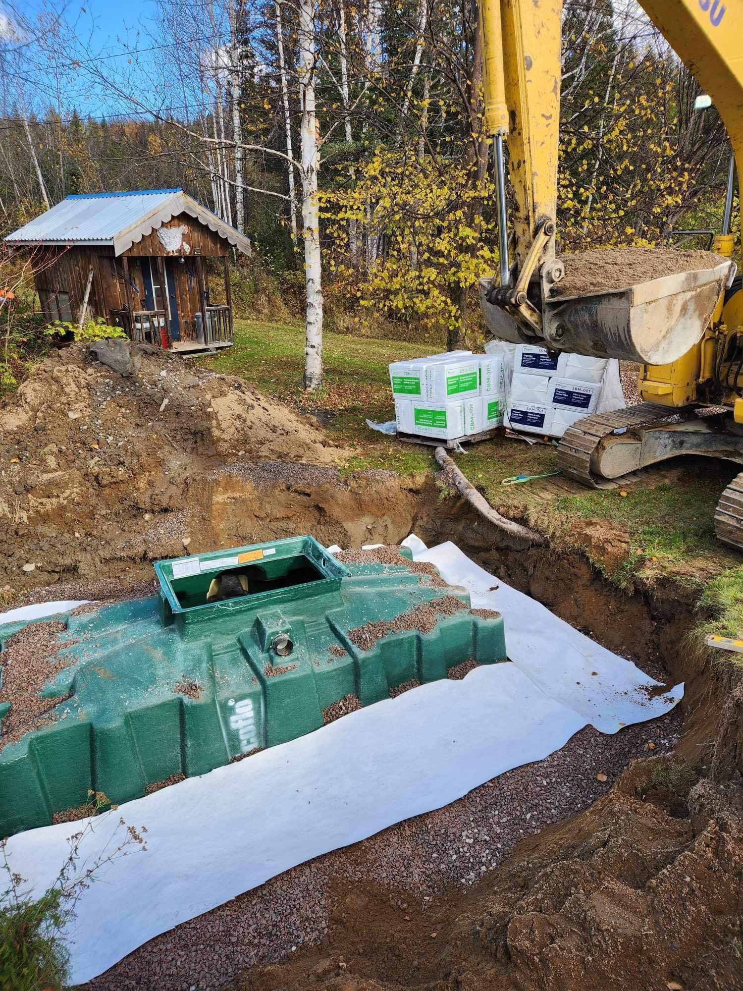 Une excavatrice jaune creuse un trou pour une fosse septique.