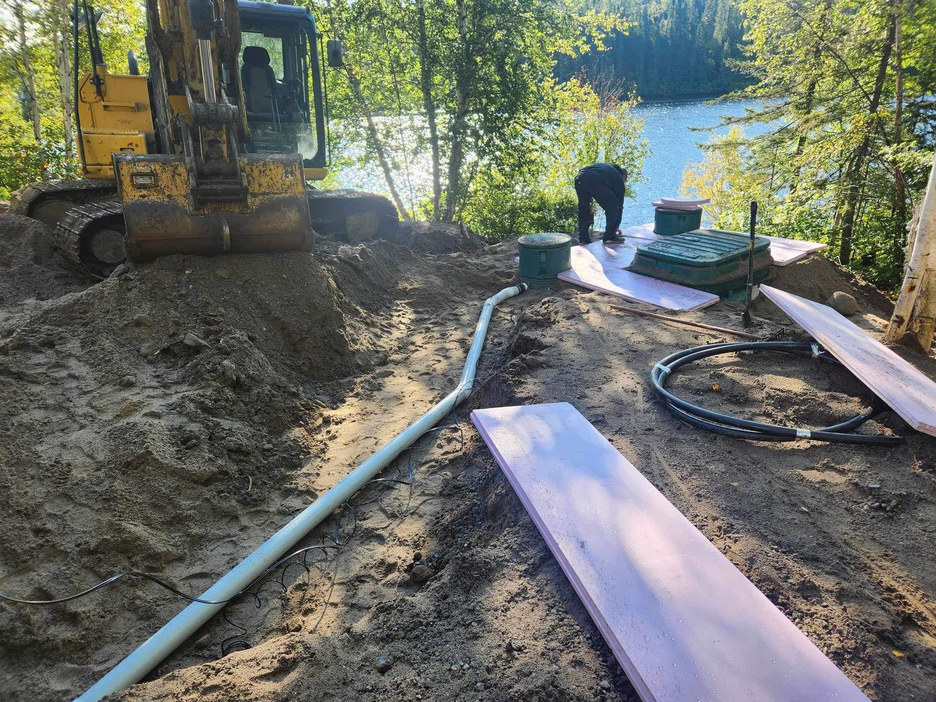 Une excavatrice jaune creuse un trou dans le sol à côté d'un lac.