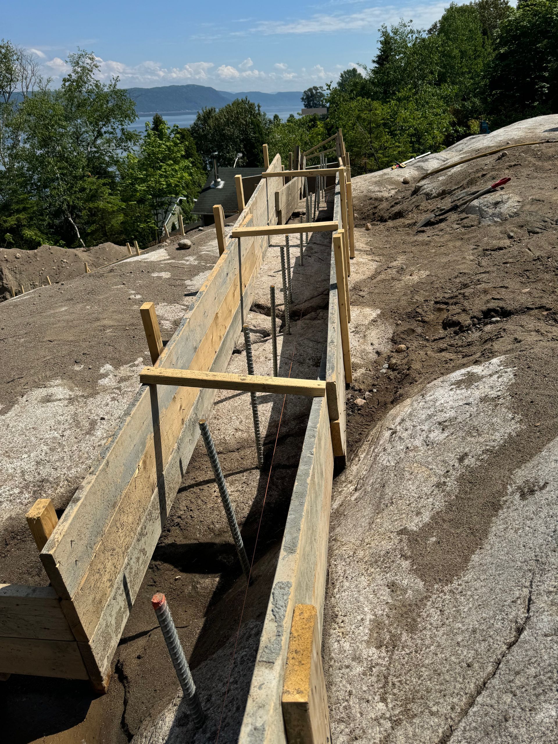 Une clôture en bois est en train d'être construite au sommet d'une colline rocheuse.