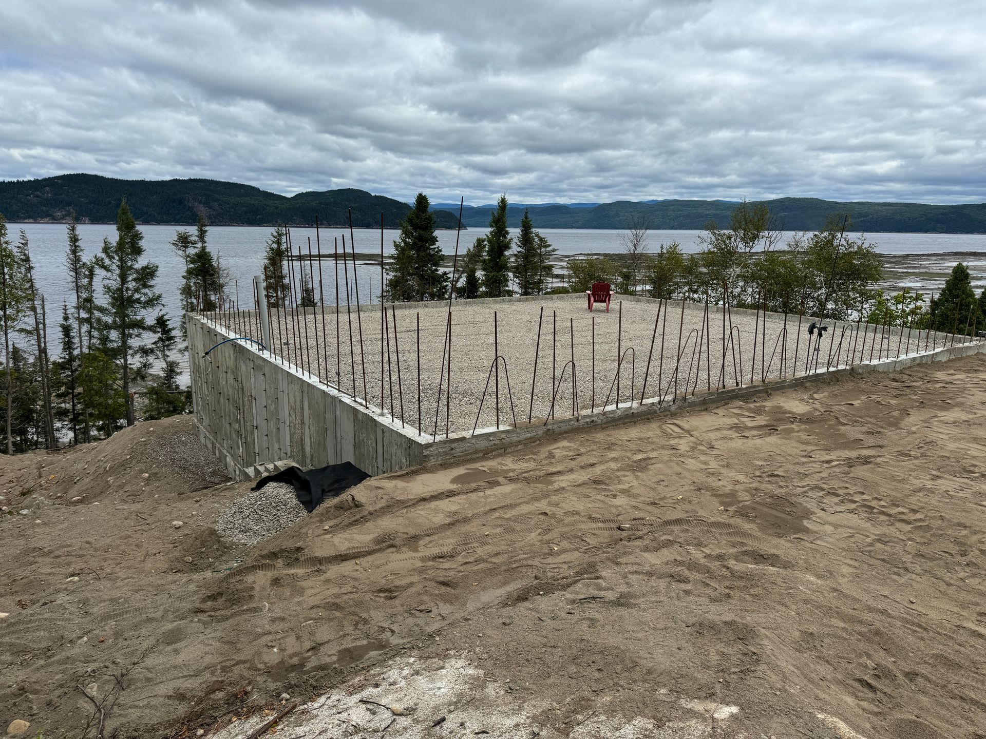 Une fondation en béton est en cours de construction sur une colline surplombant un lac.