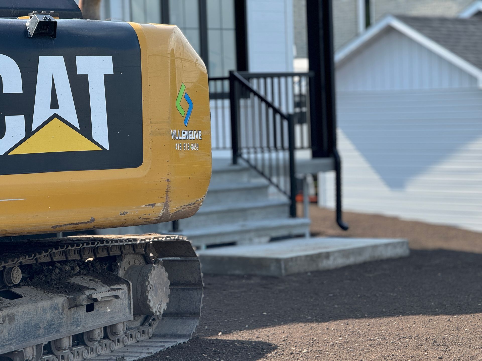 Une excavatrice à chat est garée devant une maison