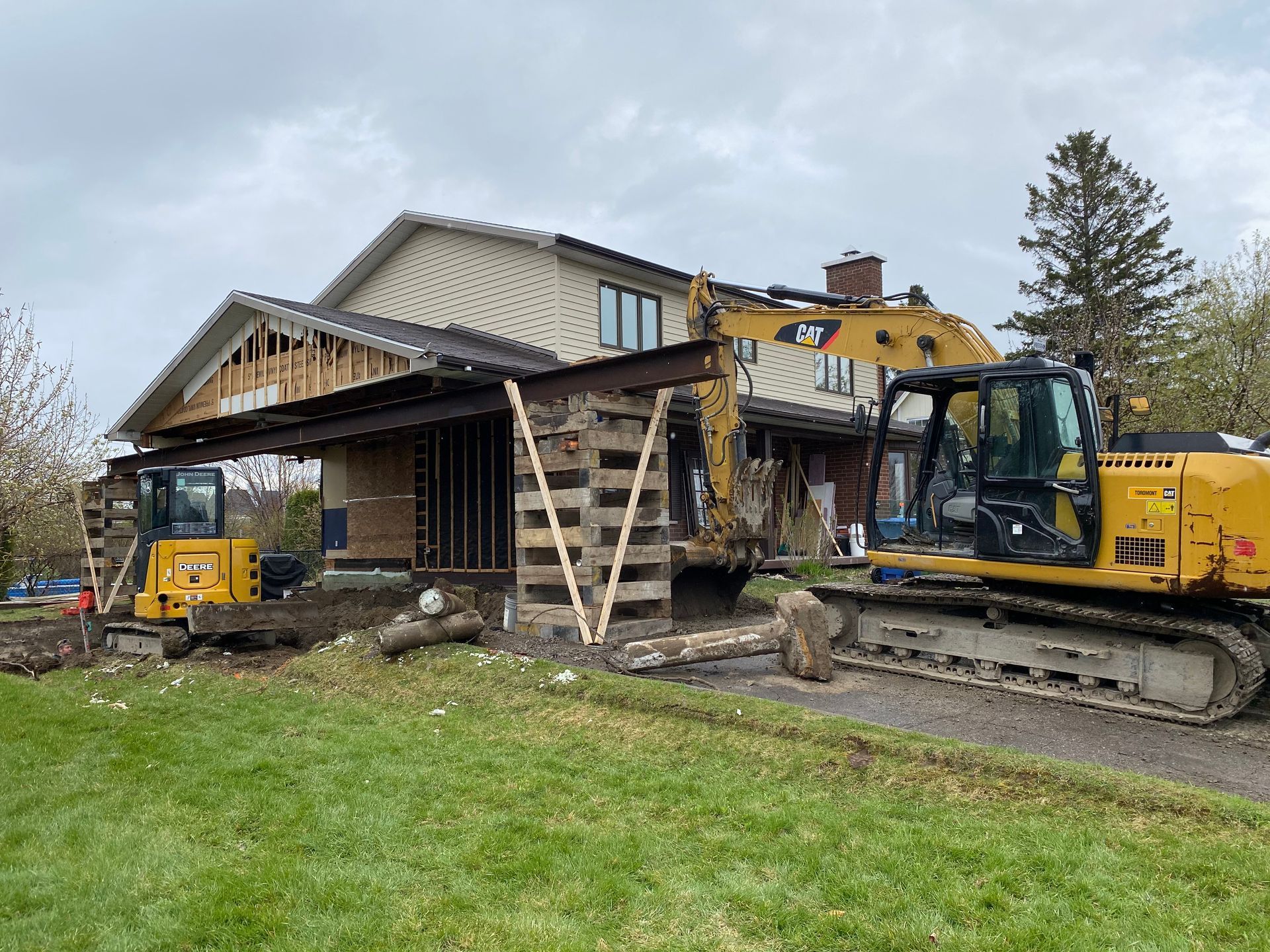 Une grande excavatrice jaune démolit une maison.