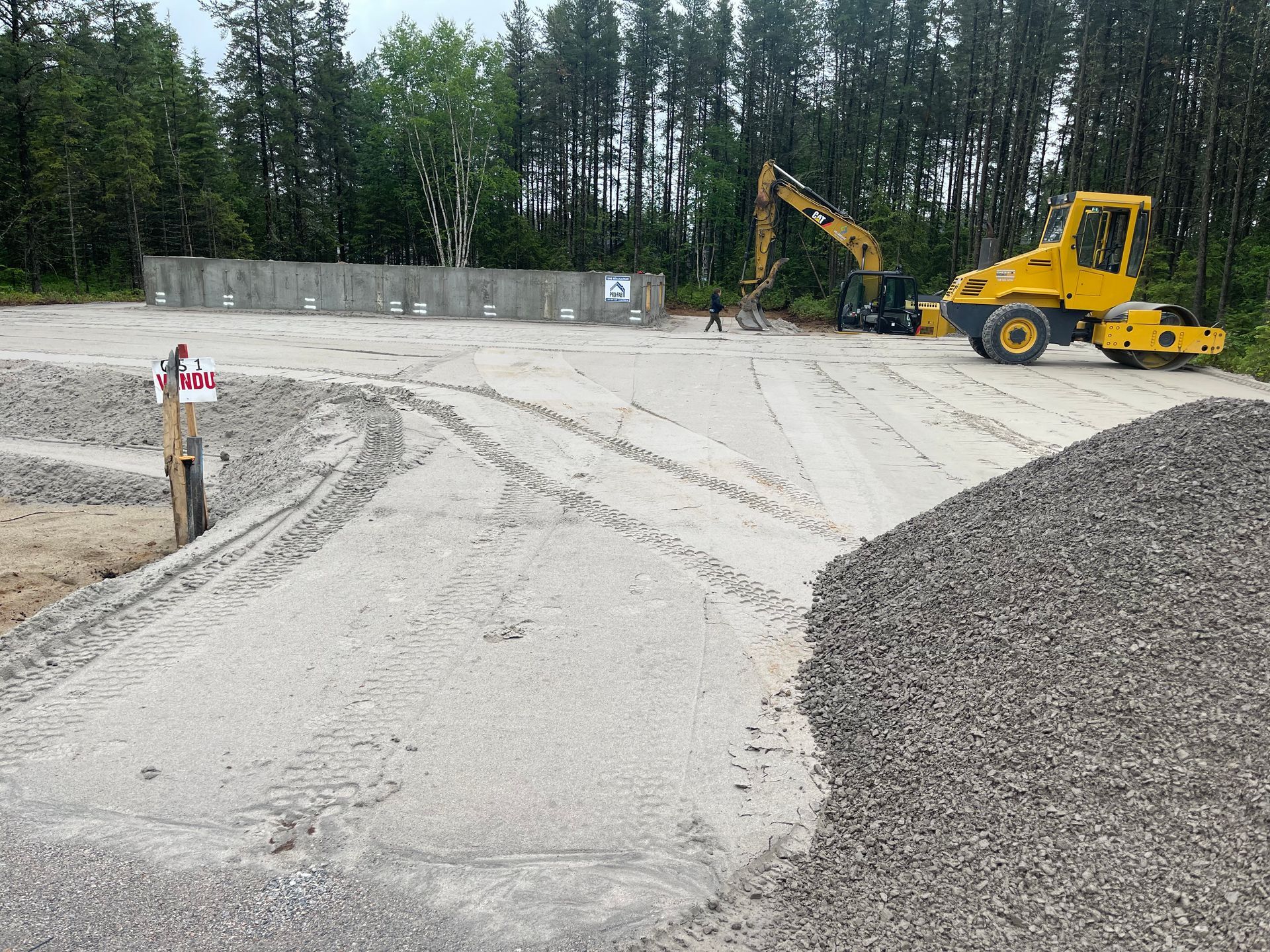 Un bulldozer jaune roule sur un chemin de terre à côté d'un tas de gravier.