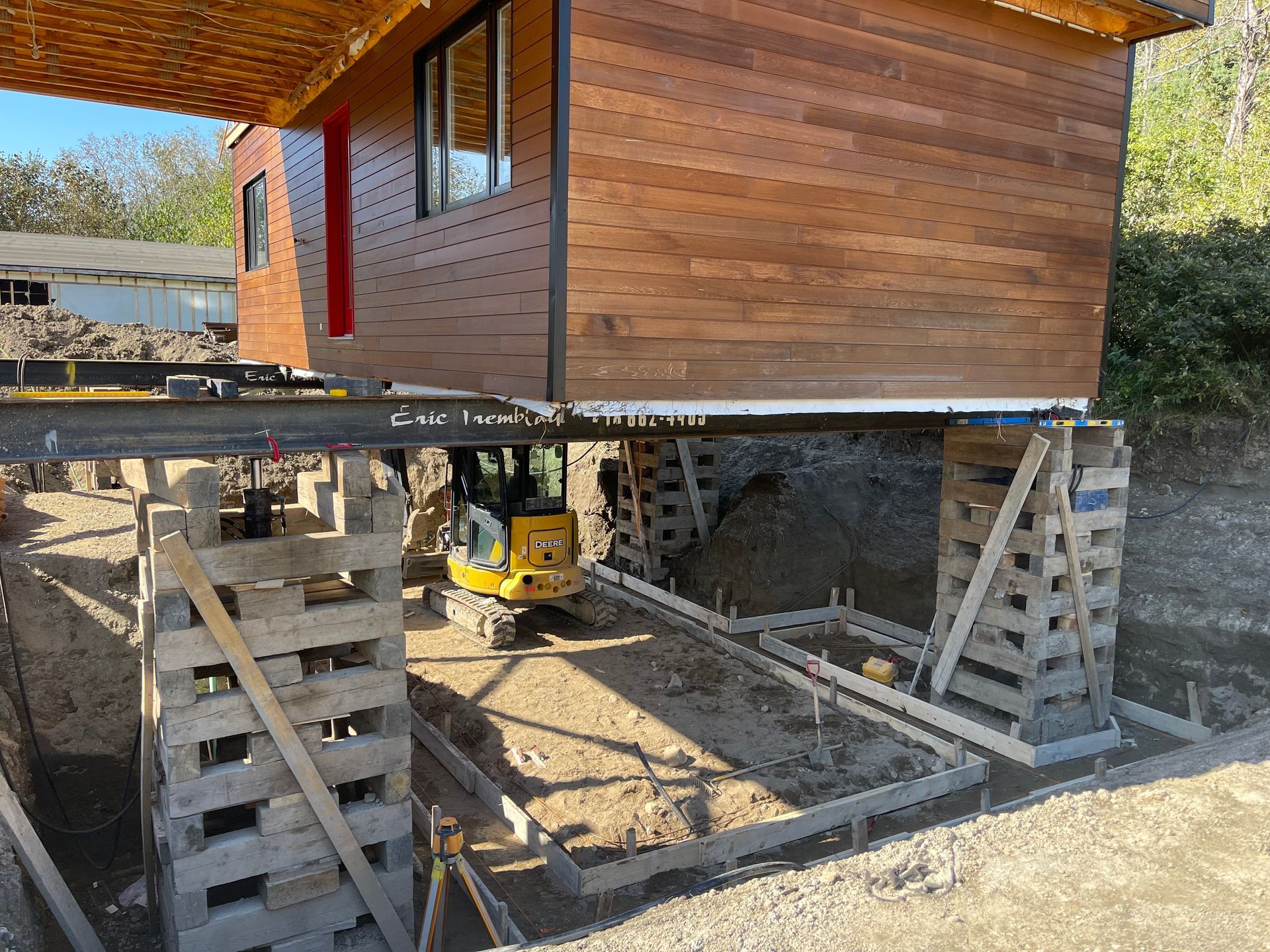 Une petite maison est soulevée dans les airs par un bulldozer.