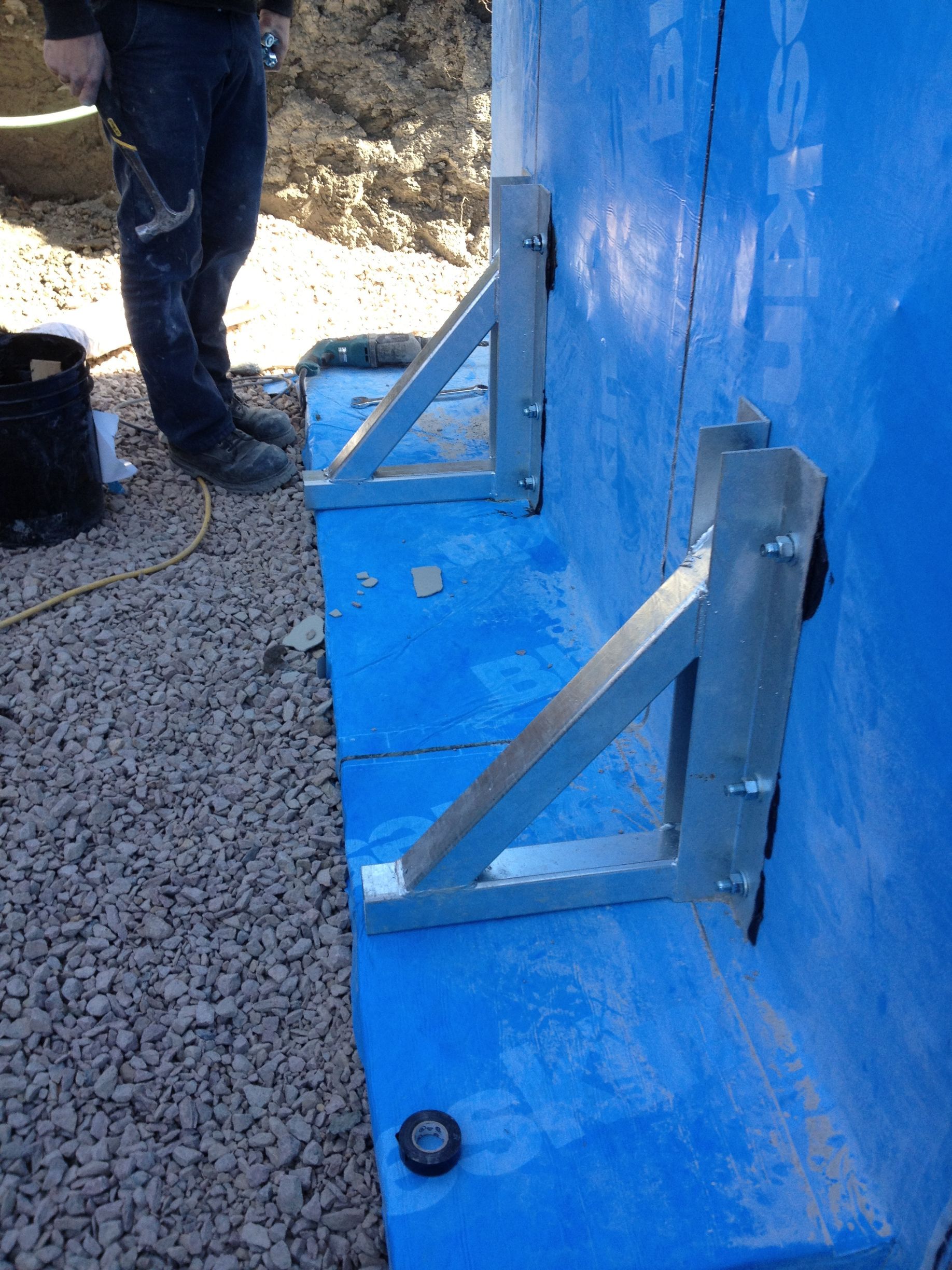 Un homme se tient à côté d'un mur bleu avec des supports métalliques dessus.